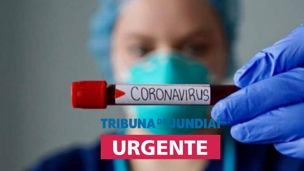 profissional de saúde com máscara e equipamentos mostra frasco com amostra de sangue com inscrição "coronavírus". A imagem tem sobreposta um logotipo escrito "Tribuna de Jundiaí Urgente"