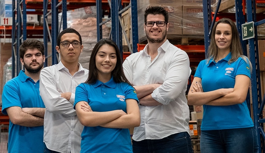 Foto de jovens com uniforme da astra posando em almoxarifado da empresa