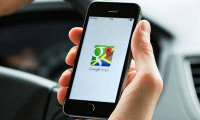 Foto de mão segurando celular com tela do aplicativo google maps aberta