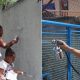 Mulheres e crianças pintando muros, à esquerda; homem pintando portão, à direita
