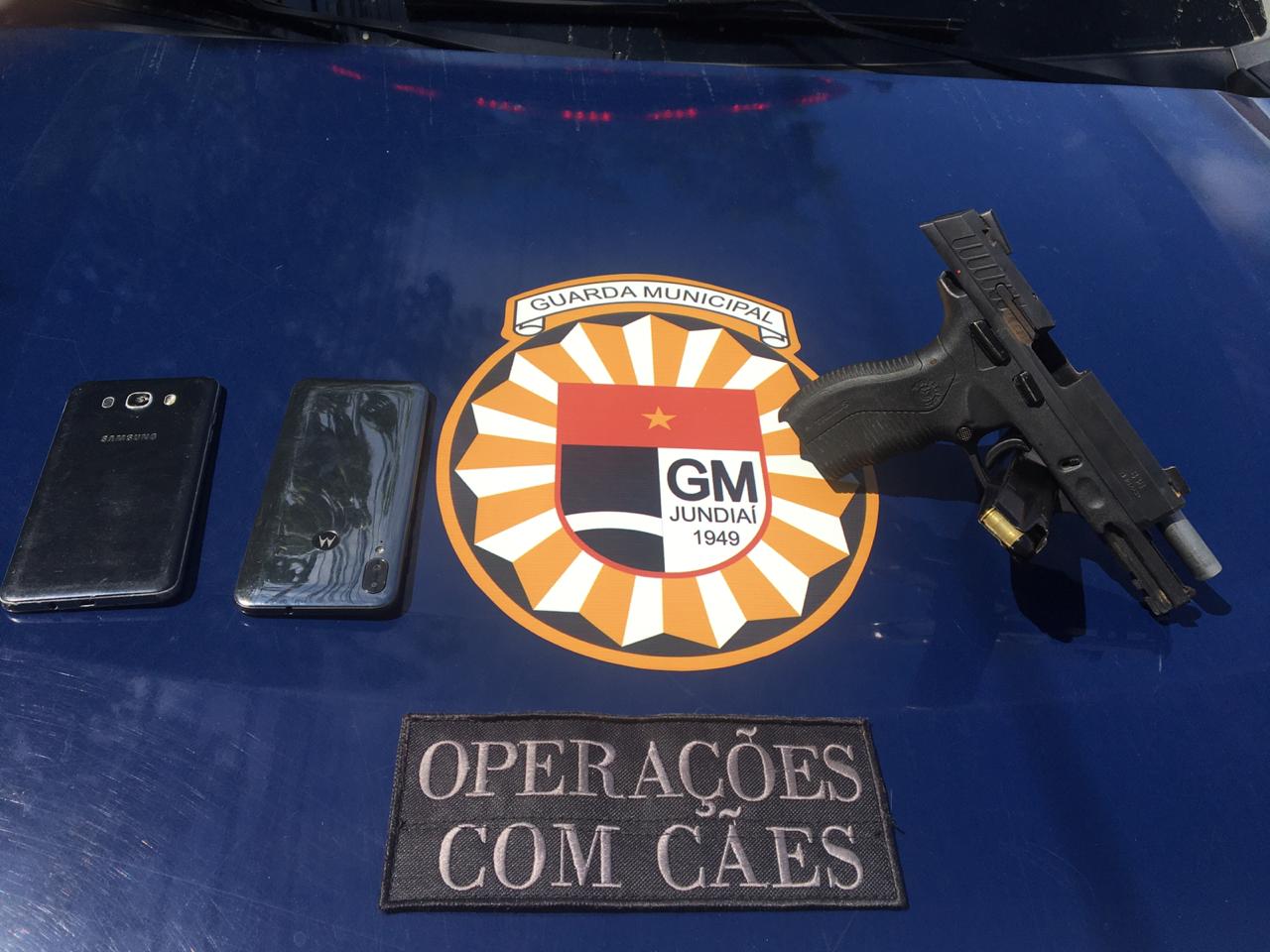 arma e celulares em cima de uma mesa com o símbolo da guarda municipal