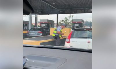 policial encostado no carro realizando bafometro