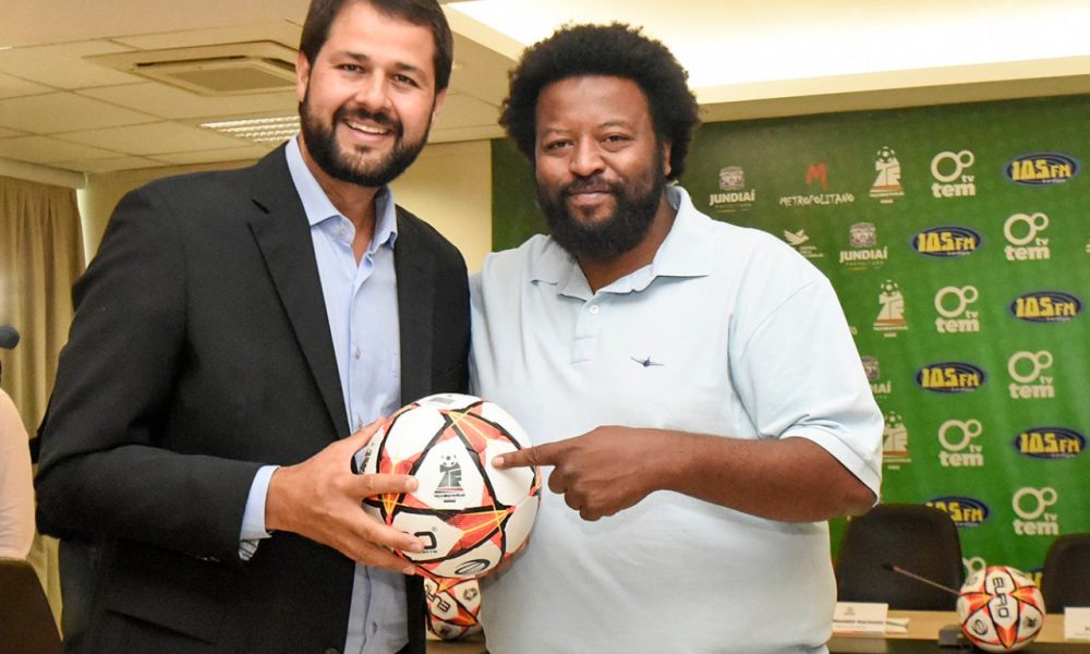 um homem branco e um homem negro segurando uma bola de futebol