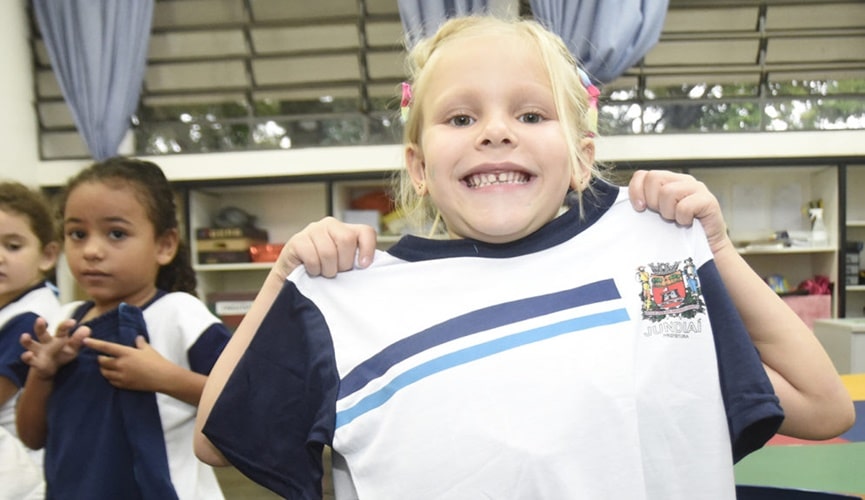 Foto de criança segurando camiseta de uniforme