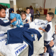 Crianças pegam uniformes espalhados por uma mesa