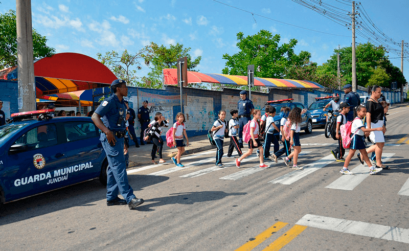 Guardas municipais auxiliam crianças atravessarem faixa de pedestres
