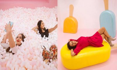 mulheres em ambiente colorido brincando com doces gigantes