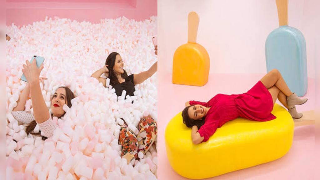mulheres em ambiente colorido brincando com doces gigantes