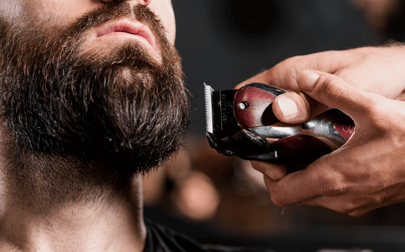 Homem barbudo segurando uma máquina de barbear