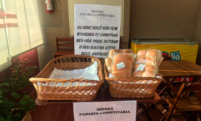 Cestas de pães com cartaz que diz que pessoas que não tem como comprar, podem pegar diretamente