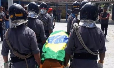 Foto de caixão sendo levado por soldados da polícia militar