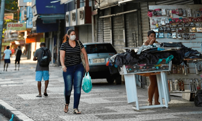 Mulher anda com máscara na calçada
