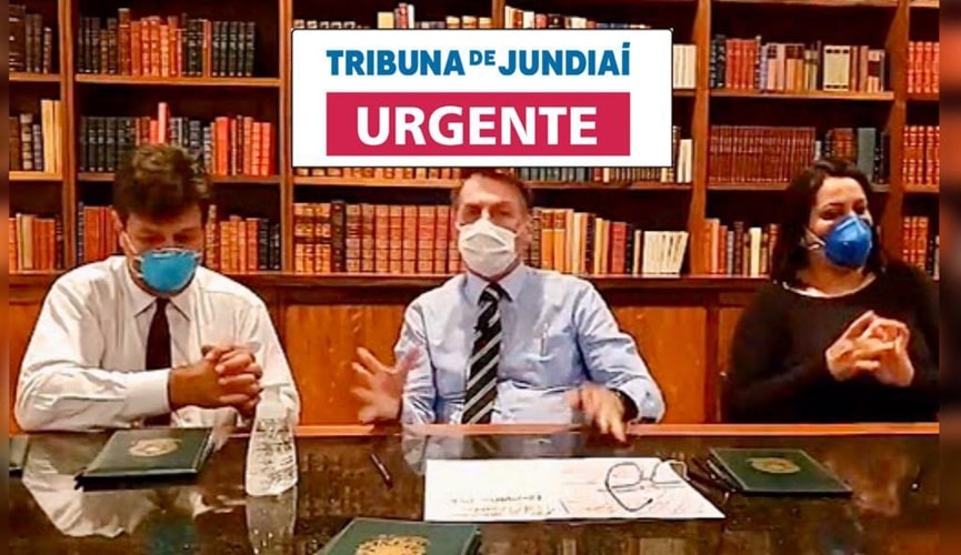 Jair Bolsonaro de máscara, no meio de outras duas pessoas com máscara
