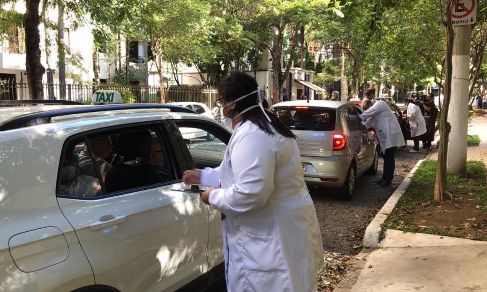 profissional de saúde faz vacinação em pessoas dentro de carros em rua