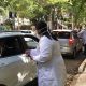 profissional de saúde faz vacinação em pessoas dentro de carros em rua