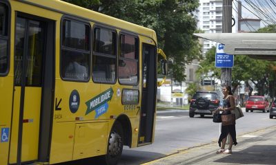 Ônibus estacionado em ponto, com mulher na porta