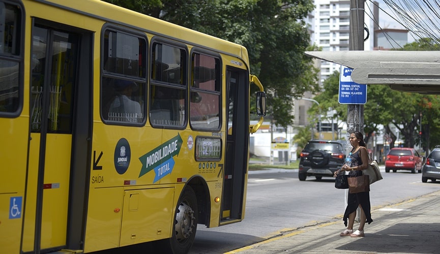 Ônibus estacionado em ponto, com mulher na porta