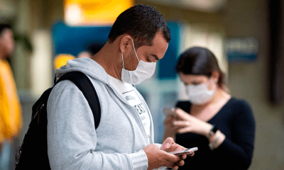 Homem com máscara mexendo no celular