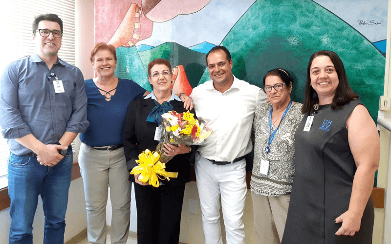 Selma Moraes, ao centro, com buquê de flores; ao lado dela, representantes do Sindicato da Saúde; funcionários do Hospital São Vicente e superintendente.