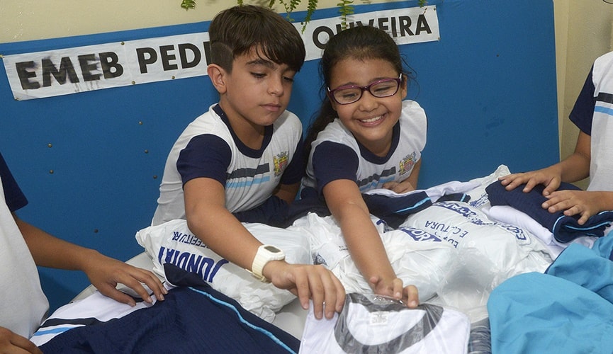 Crianças segurando uniformes escolares