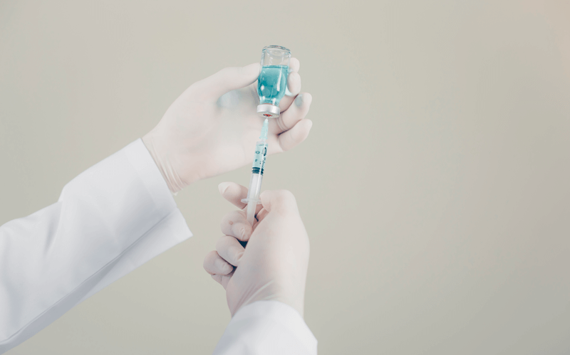 Trabalhador manuseia vacina e seringa
