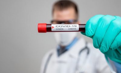 Médico segura tubo de ensaio com sangue e etiqueta de COVID-19