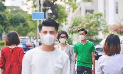 Pessoas andam em centro urbano usando máscaras