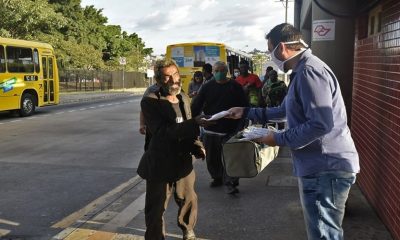 Foto de passageiros recebendo máscaras de proteção