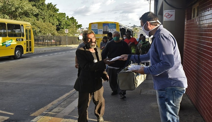 Foto de passageiros recebendo máscaras de proteção