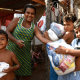 Mãe e três filhos seguram cestas básicas em frente a sua casa