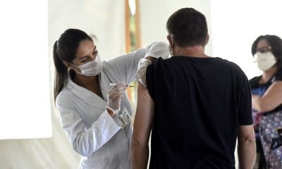 Foto de mulher aplicando vacina em homem