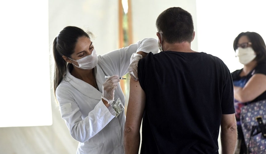 Foto de mulher aplicando vacina em homem