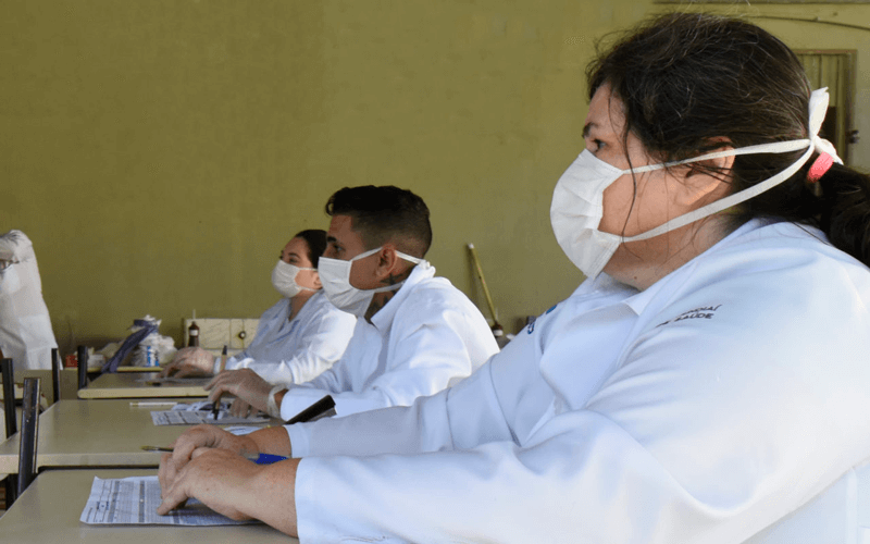 Pessoas estão usando jaleco branco e máscaras cirúrgicas