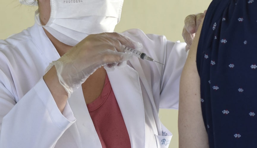Foto de enfermeira aplicando vacina em idosa