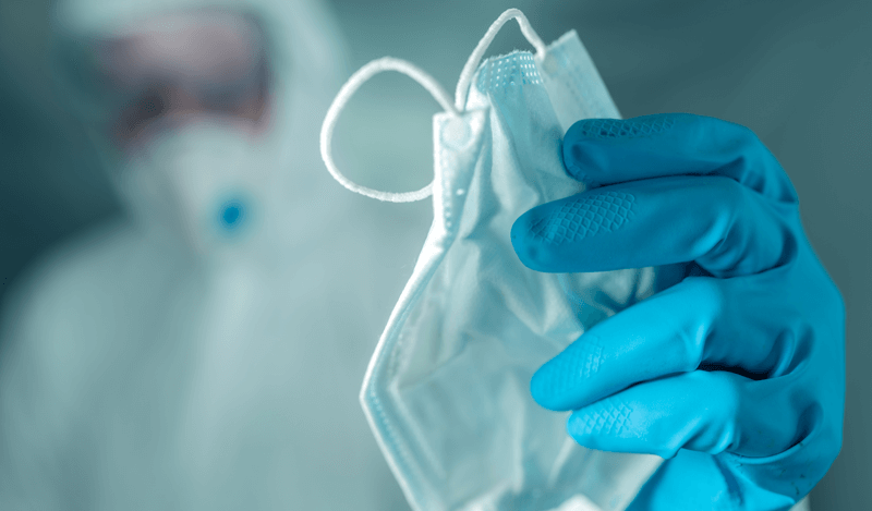 Médico segura máscara cirúrgica nas mãos com luvas