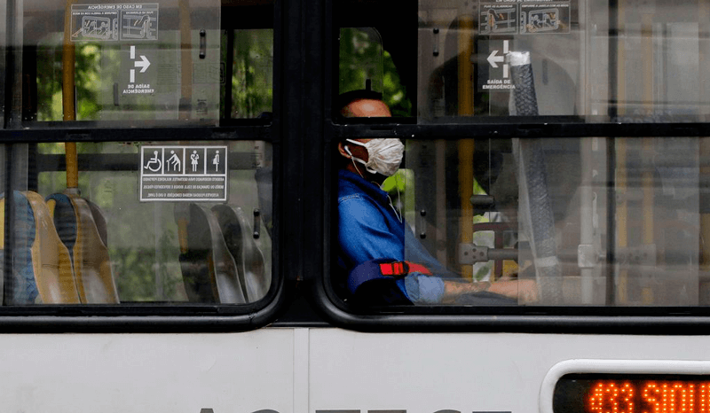 Pessoas usando máscara em ônibus