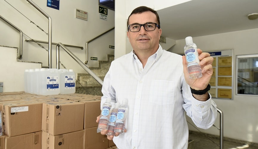 Foto de homem segurando frascos de álcool em gel