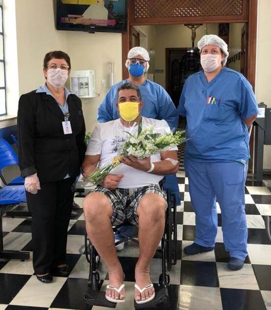 Homem sai do Hospital São Vicente na cadeira de rodas com flores nas mãos