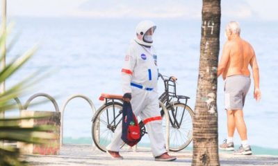 Homem passeando pela praia vestido de astronauta