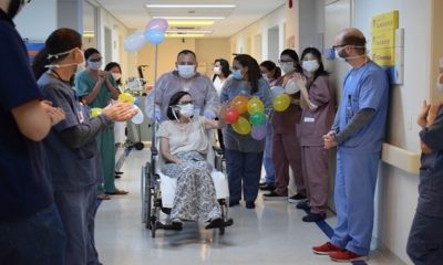 Foto de mulher em cadeira de rodas, deixando hospital com bela homenagem de enfermeiros