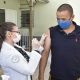 Foto de enfermeira aplicando vacina em homem