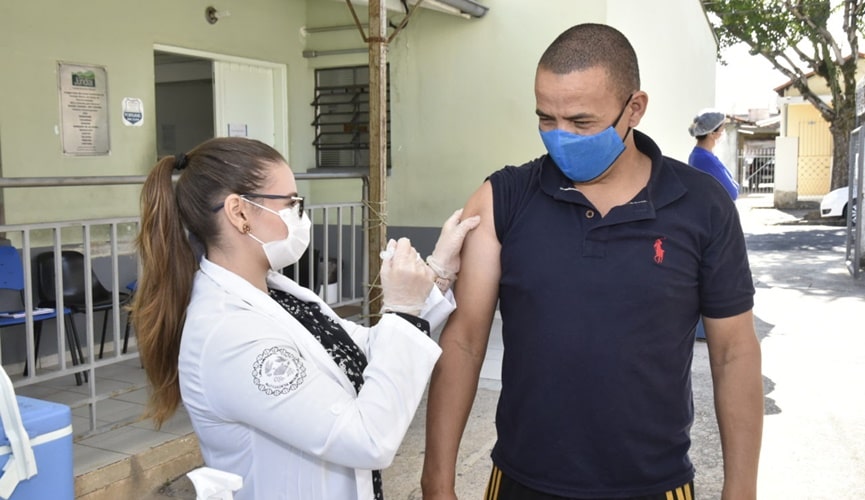 Foto de enfermeira aplicando vacina em homem