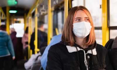 Menina com máscara anda de ônibus