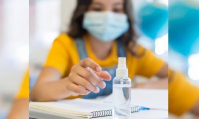 Criança em sala de aula com máscara e álcool em gel