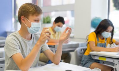 Alunos em sala de aula com máscara e álcool em gel