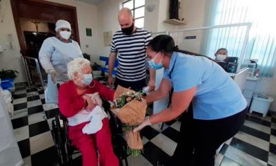 Mulher de cabelos brancos deixando hospital em cadeira de rodas