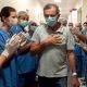 Homem sai do Hospital passando por corredor de profissionais de saúde que batem palmas em comemoração à recuperação