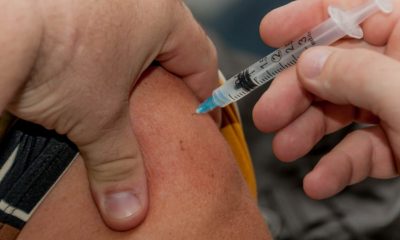Mãos aplicando vacina no braço de outra pessoa