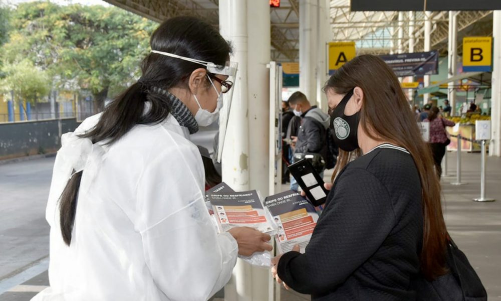 Profissional da Saúde mostrando folheto para passageira no Terminal Central