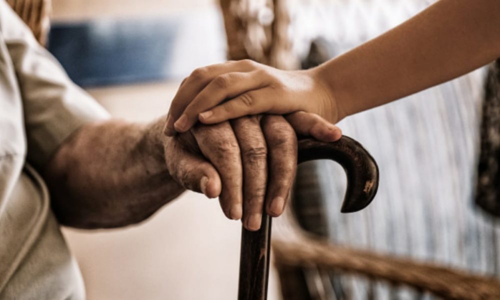 Pessoa segurando a mão de um idoso